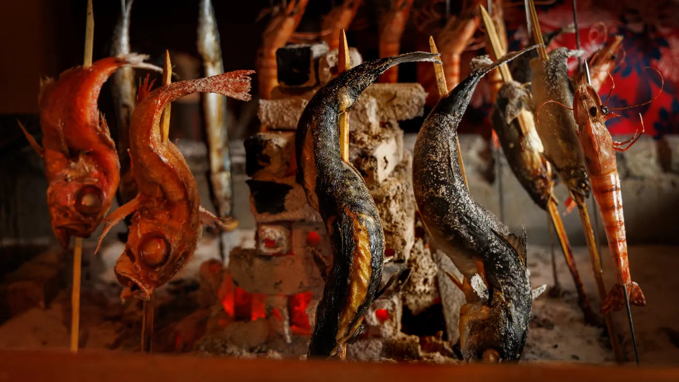 炉端で串打ちした魚介を炭火で焼き上げる原始焼きの様子